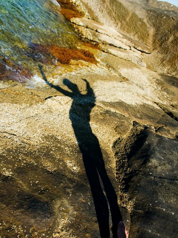 ombra di Due persone su rocce vicino acqua foto