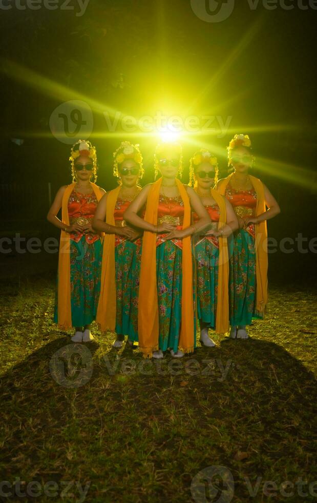 un' gruppo di indonesiano tradizionale ballerini danza con loro amici nel davanti di il palcoscenico luci foto