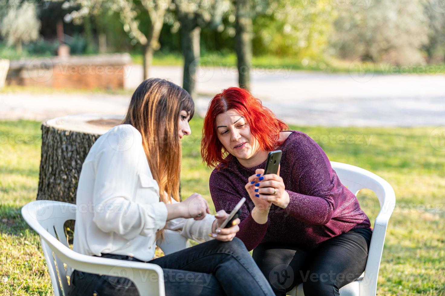 amiche che usano smartphone e fumano sigarette foto