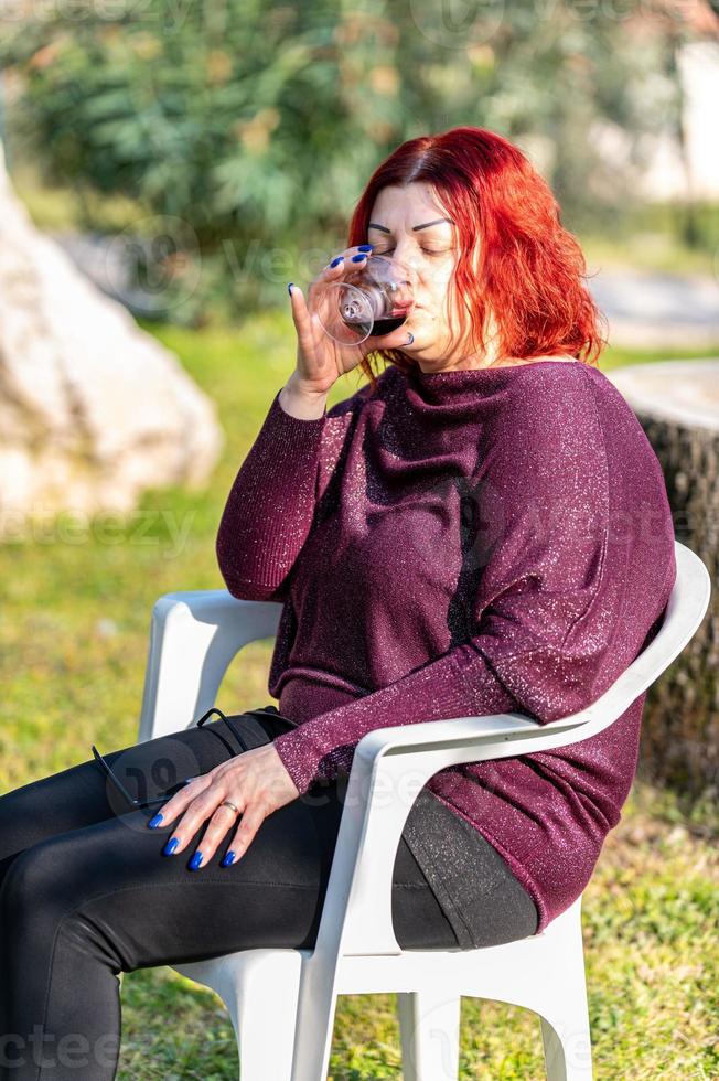 la ragazza beve un calice di vino rosso in giardino foto