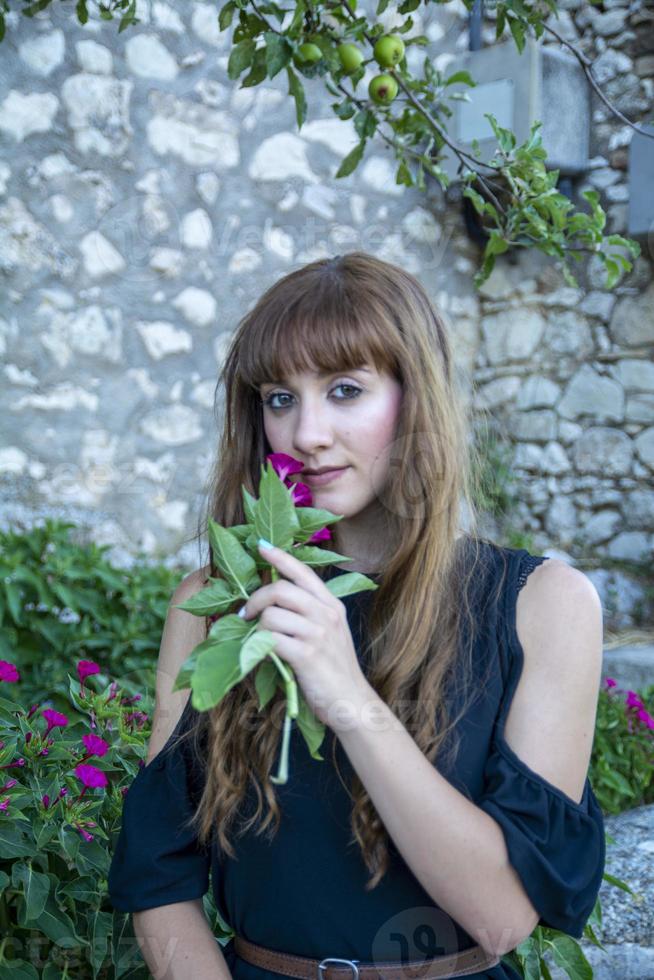 una ragazza dai capelli lunghi che annusa fiori foto