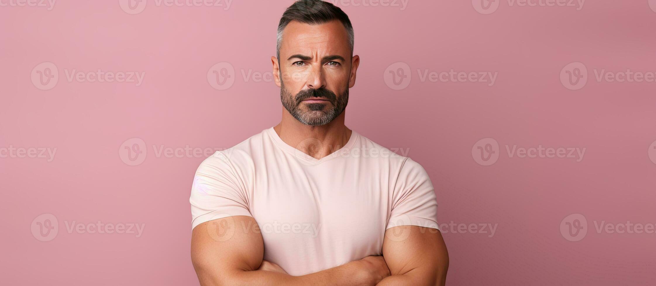 grave uomo in posa con attraversato braccia guardare a telecamera rosa studio sfondo foto