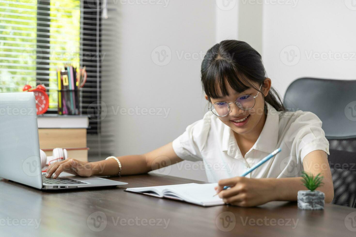 alunno ragazza contento studiando in linea, indietro per scuola concetto. giovane donna alunno occupato studia rendere Appunti nel taccuino e utilizzando il computer portatile concentrato in linea formazione corso tecnologia formazione scolastica. foto