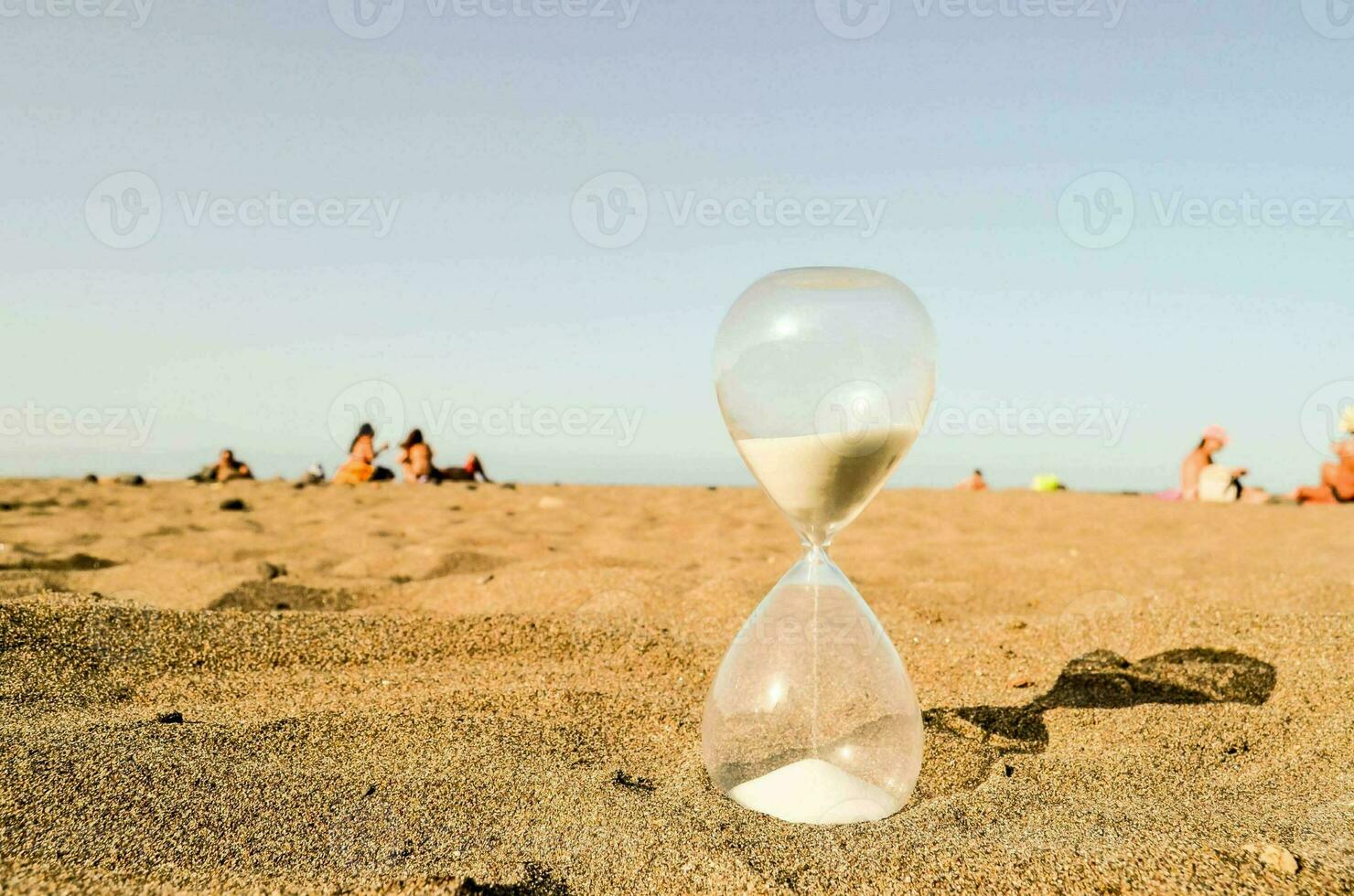 un clessidra su il spiaggia con persone nel il sfondo foto