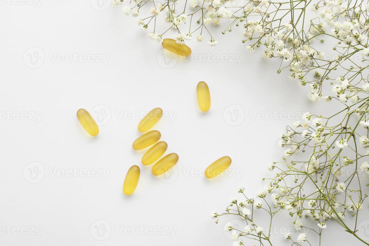 capsule di gel di olio di fegato di merluzzo omega 3 isolate su sfondo bianco. capsule di gel di olio di pesce con un bouquet di fiori primaverili. vitamine foto