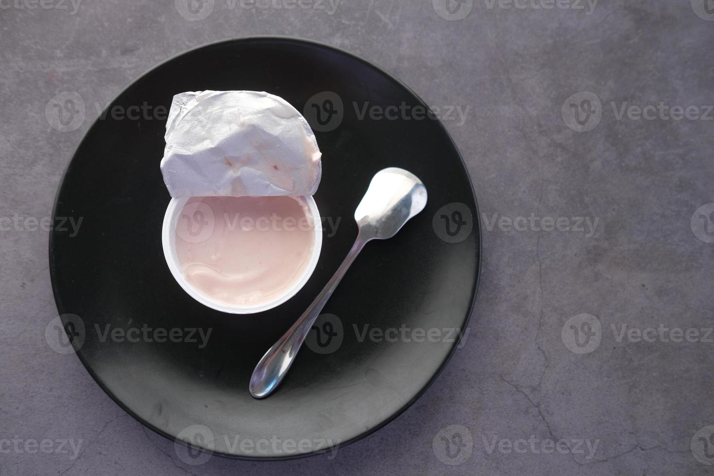 yogurt fresco in un contenitore di plastica su sfondo nero foto