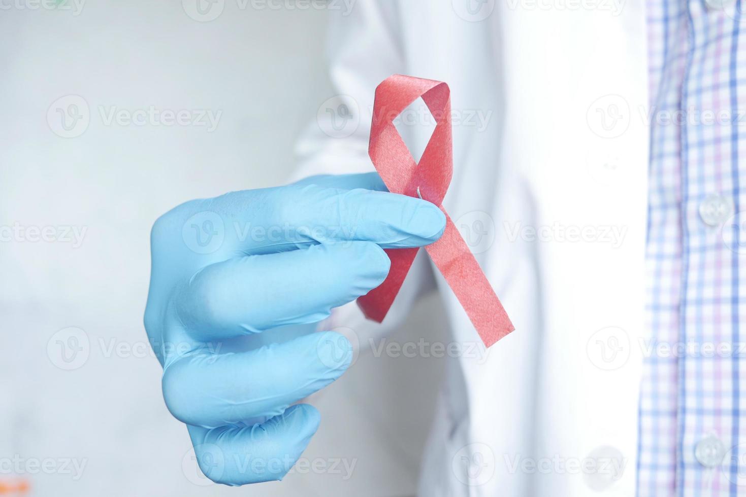 mano del dottore che tiene il nastro dell'hiv di colore rosa da vicino foto
