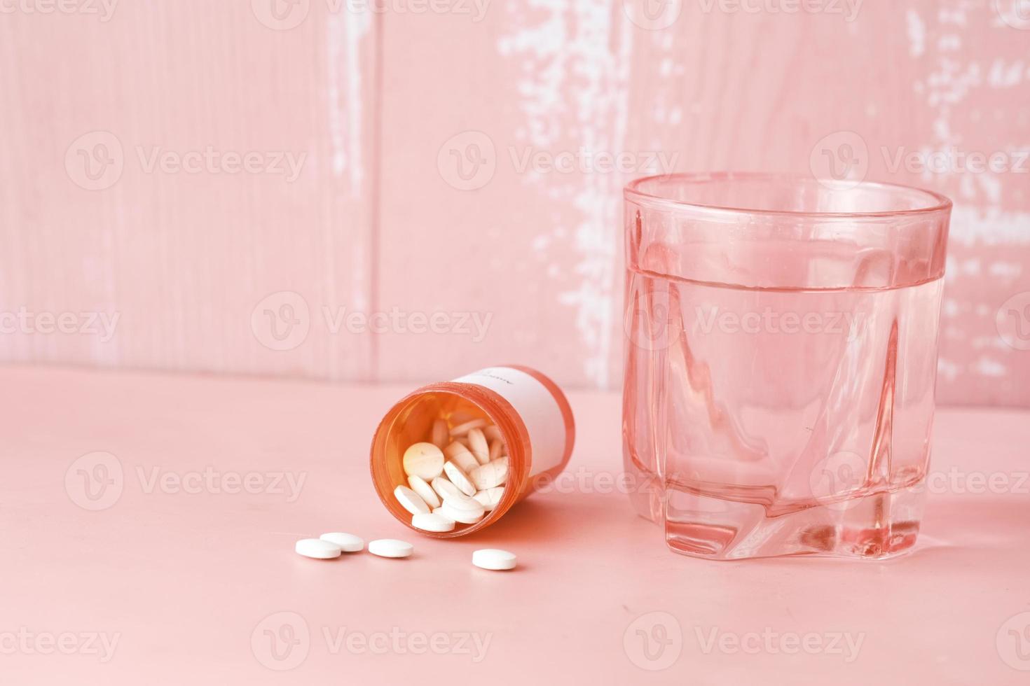 pillole mediche di colore bianco che si rovesciano sul rosa foto