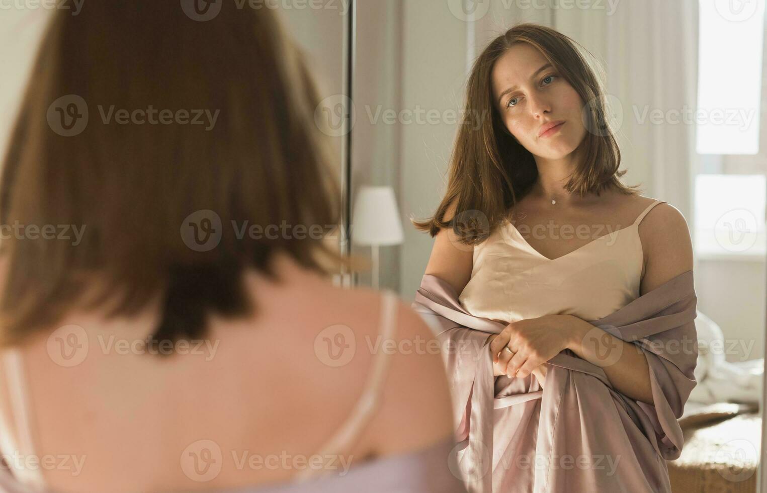 contento mattina ritratto. attraente giovane donna guardare nel specchio a sua appartamento - scia su e nuovo giorno foto