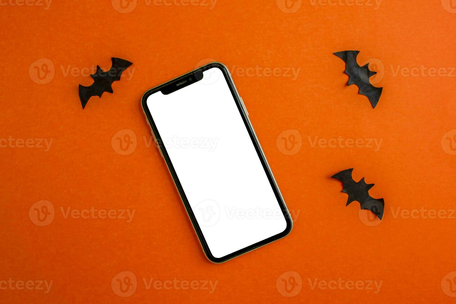 modello, smartphone e carta nero pipistrelli su arancia sfondo. Halloween sfondo. foto