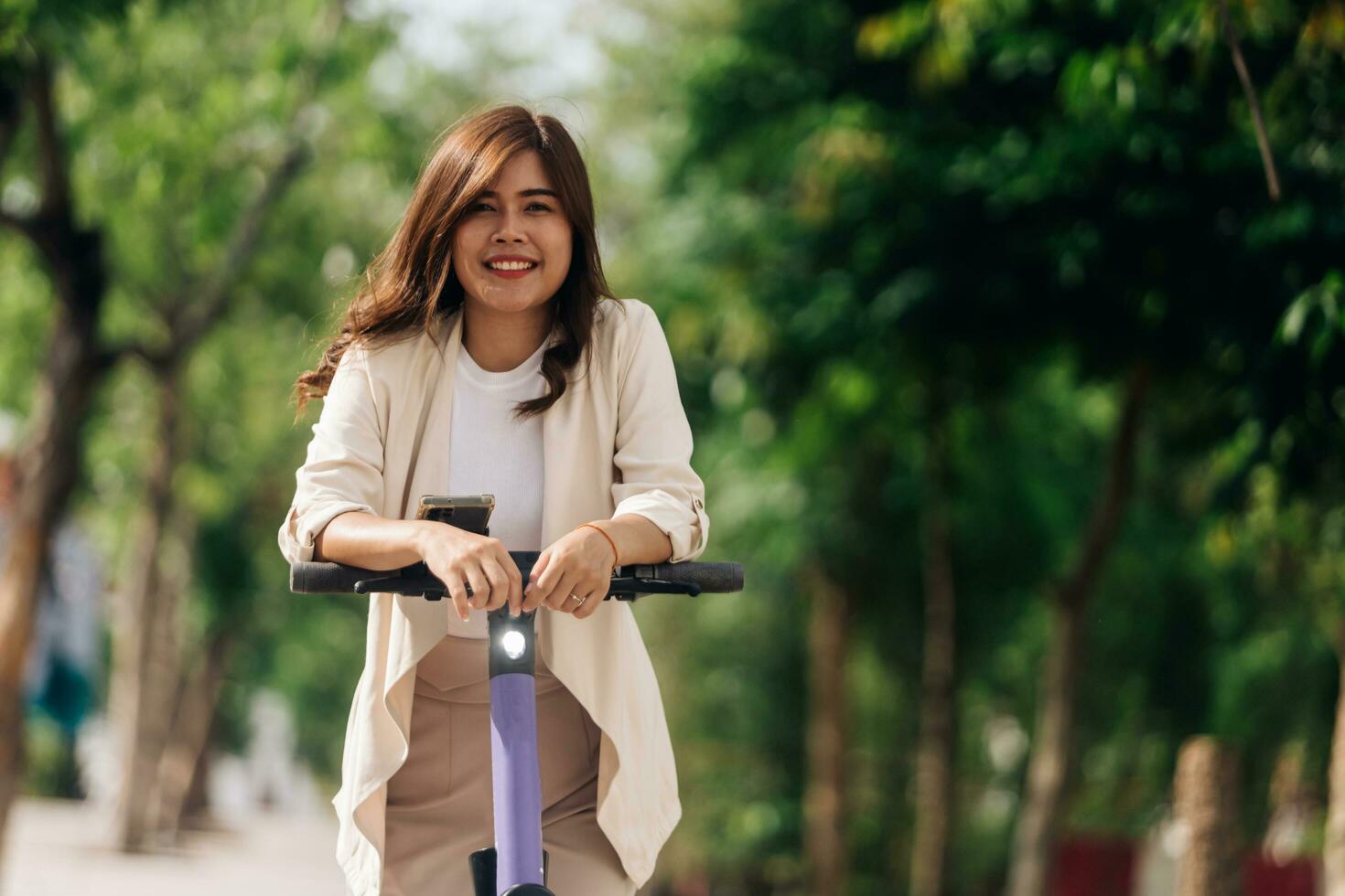 ritratto di giovane asiatico donna equitazione elettrico scooter nel parco foto