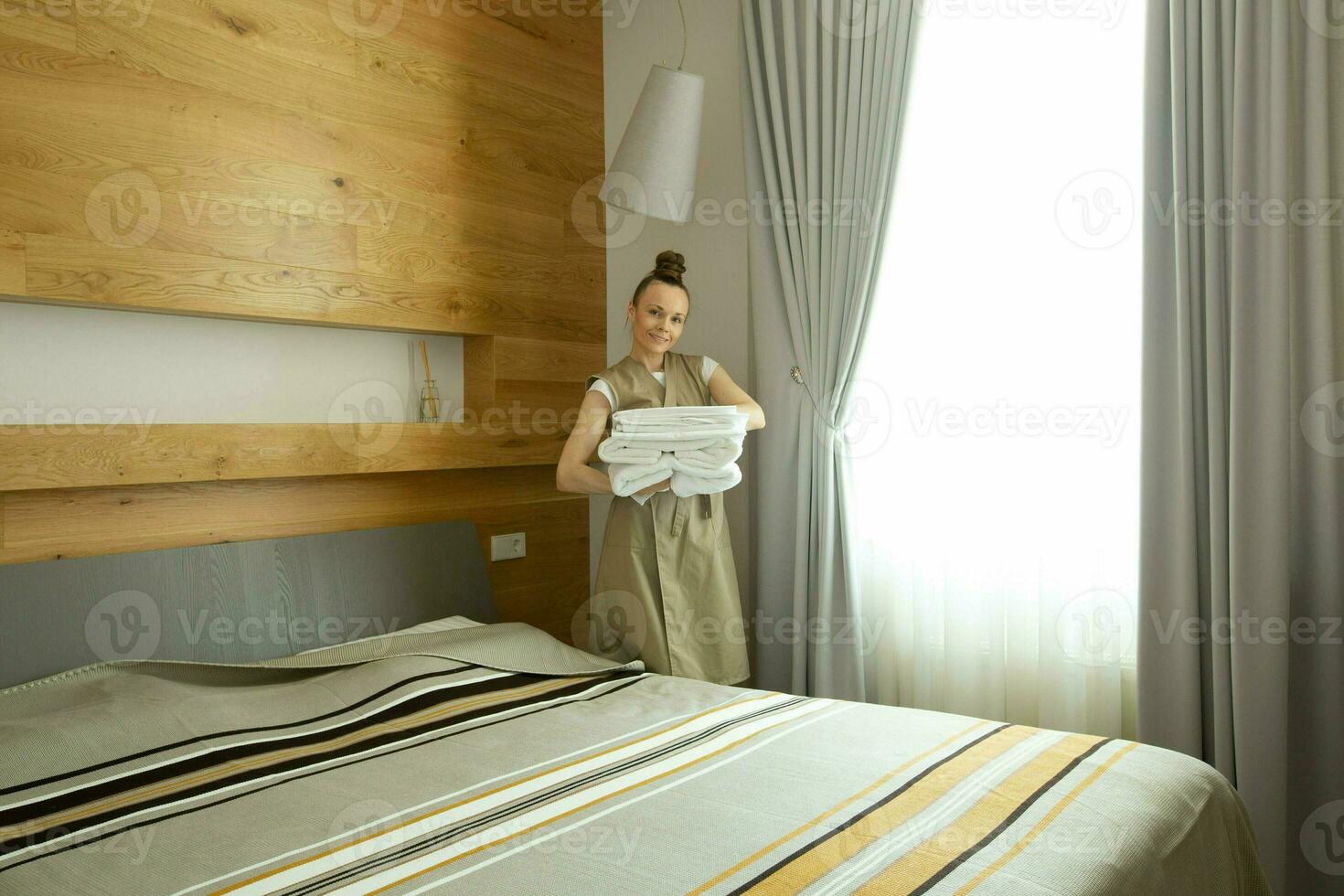 un' donna è mettendo un' coperta su un' letto foto