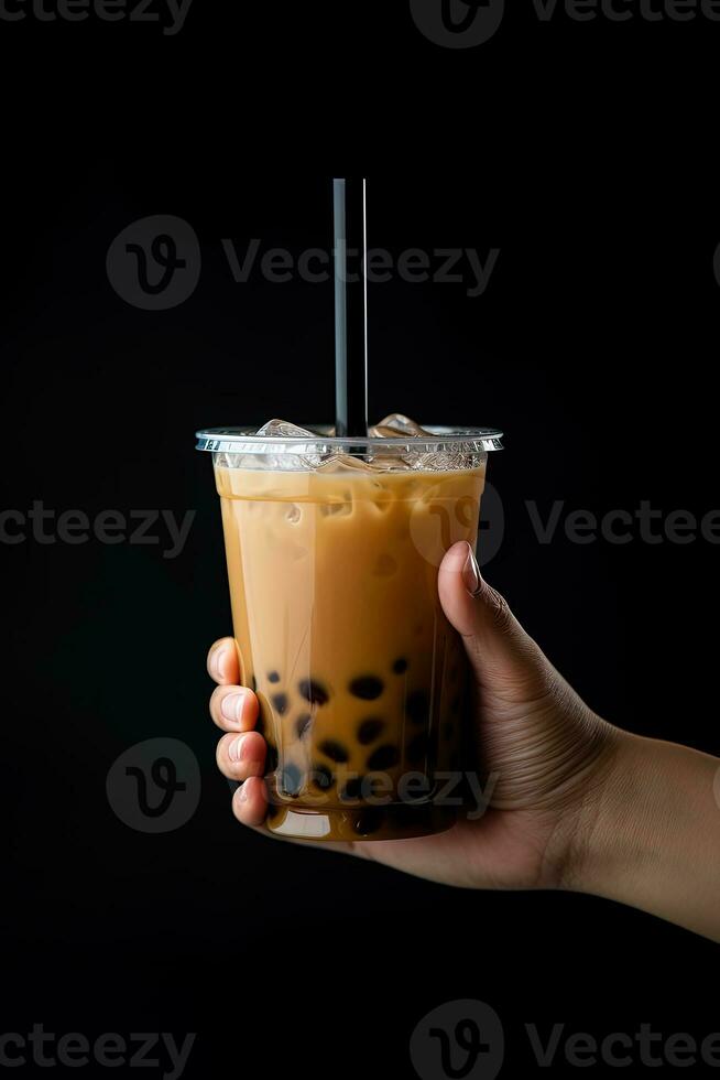 un' mano Tenere porta via plastica tazza di delizioso ghiacciato bolla latte tè e nero perle isolato su nero sfondo. ai generato foto