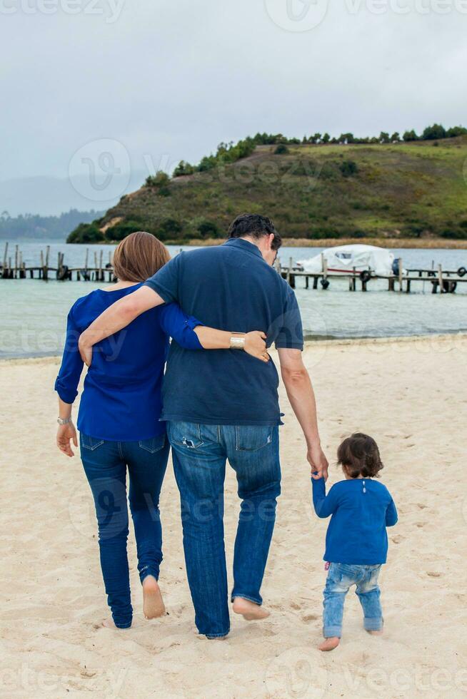 giovane coppia in attesa per loro secondo bambino avendo divertimento con loro bambino ragazza a il bellissimo bianca spiaggia di lago tota collocato nel il Dipartimento di boyaca a 3.015 metri sopra mare livello nel Colombia foto