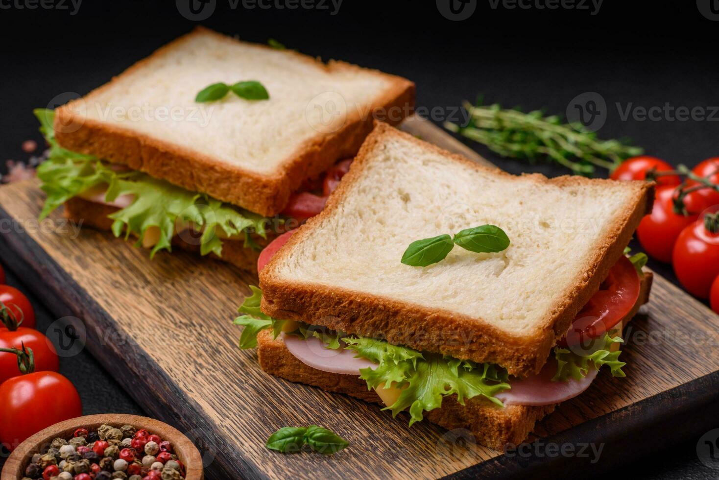 delizioso Sandwich con pane abbrustolito, prosciutto, pomodori, formaggio e lattuga foto