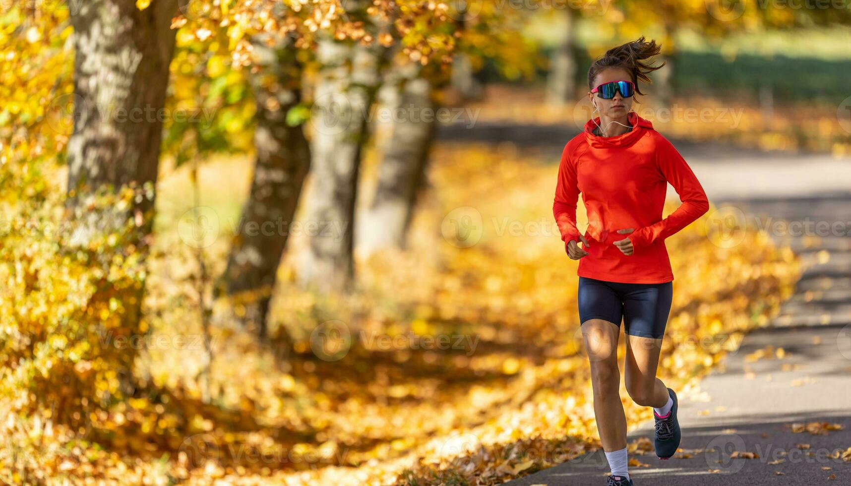 giovane femmina atleta nel abbigliamento sportivo corre nel il parco durante caldo indiano estate foto