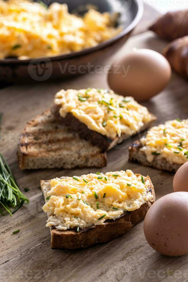 toast di pane con generoso porzione di strapazzate uova su superiore di esso, spruzzato con appena tritato erba cipollina foto