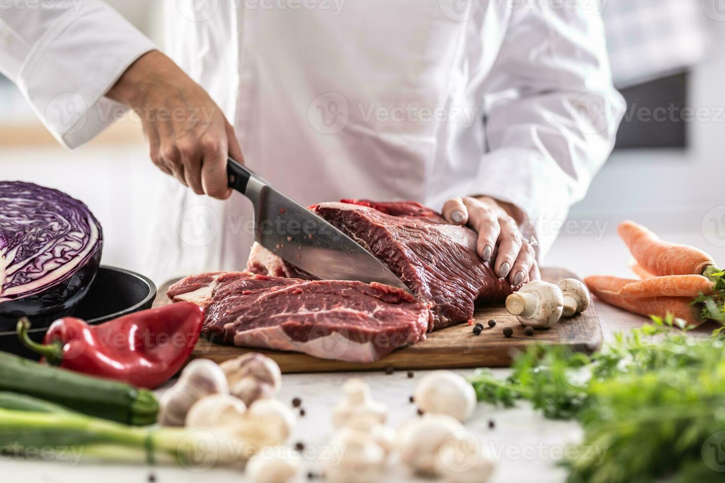 affettare Manzo o Maiale pezzo con coltello nel un' professionale ristorante cucina foto