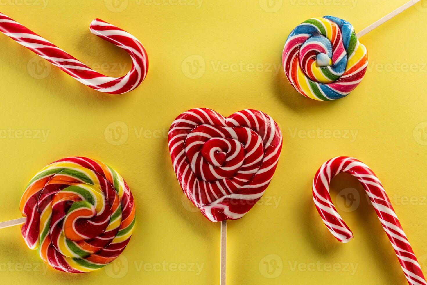 un' gustoso impostato di dolce caramelle piace Lecca-lecca con arcobaleno colore e giallo sfondo foto