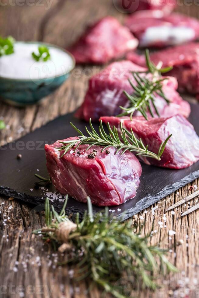 crudo Manzo carne. crudo Manzo filetto di manzo bistecca su un' taglio tavola con rosmarino Pepe sale nel altro posizioni. foto