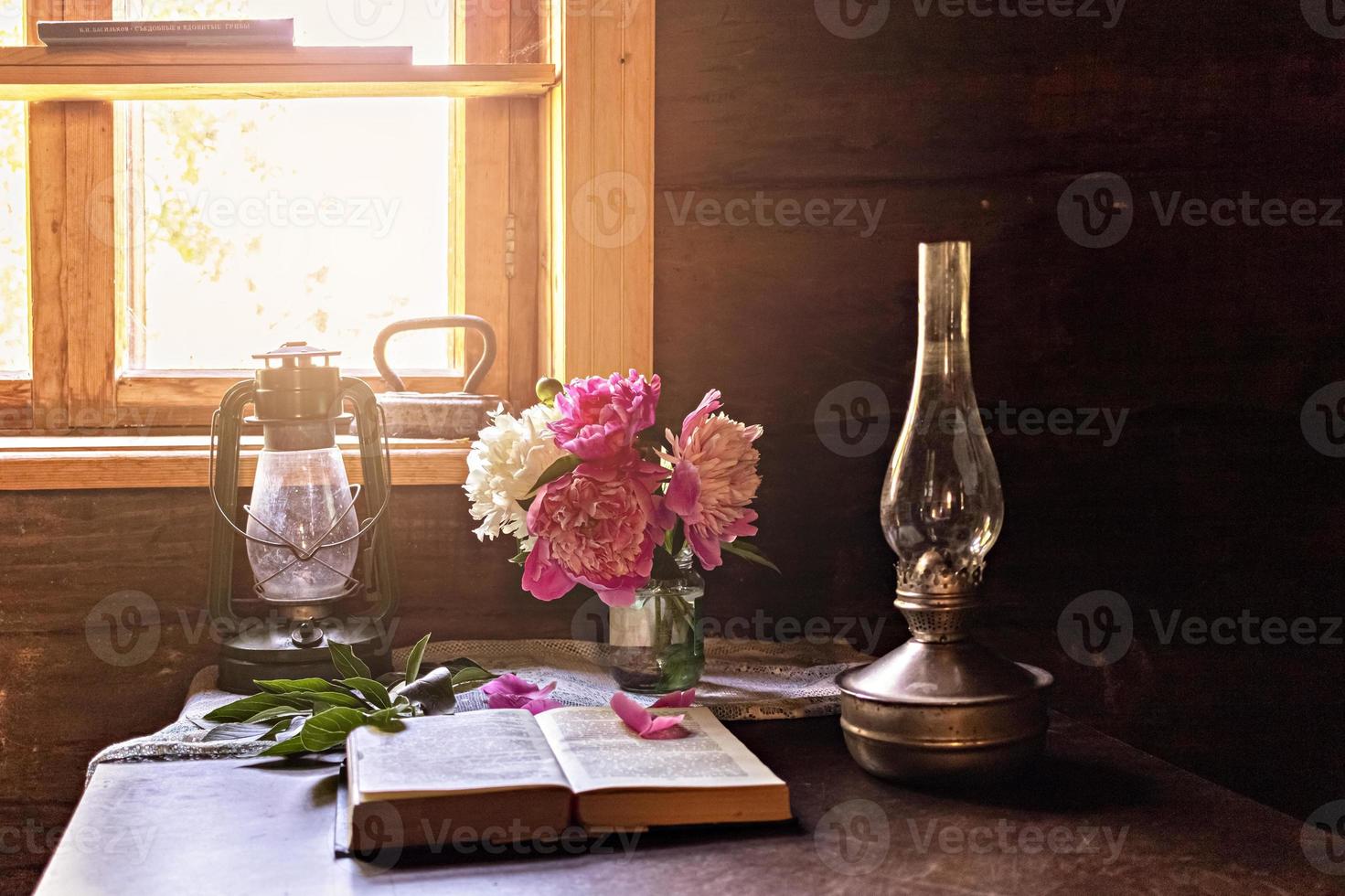 natura morta di oggetti vintage e un bouquet di peonie su un tavolo vicino alla finestra foto