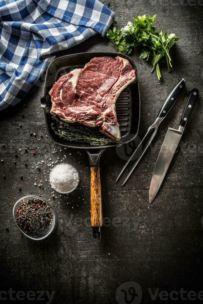 costola occhio bistecca nel griglia padella con erbe aromatiche sale Pepe forchetta e coltello foto