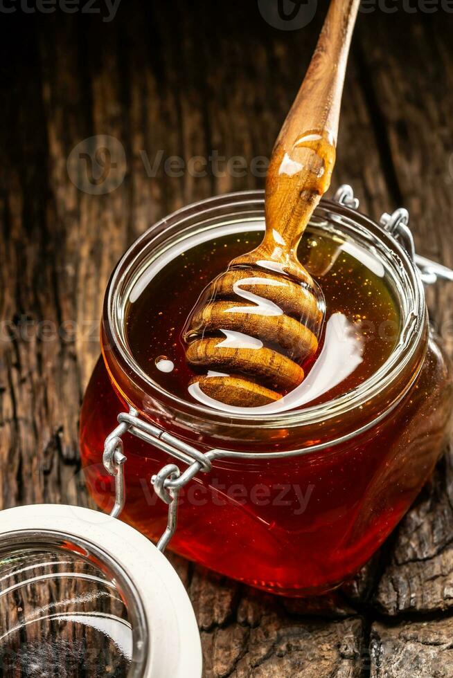 vaso di miele con mestolo su di legno tavolo - avvicinamento foto