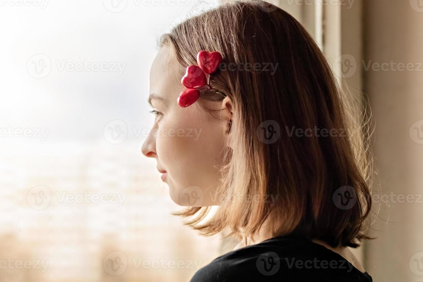 ritratto di una bella ragazza felice che guarda fuori dalla finestra con speranza e aspettativa foto