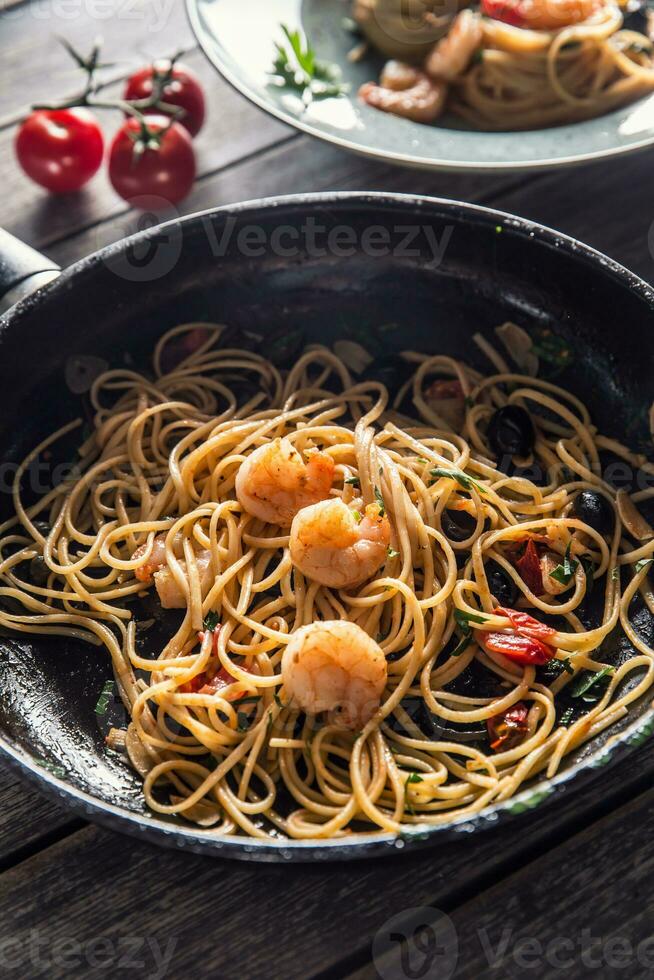 pasta spaghetti su piatto e padella con gamberetto pomodoro salsa pomodori e erbe aromatiche. italiano o mediterraneo cucina foto