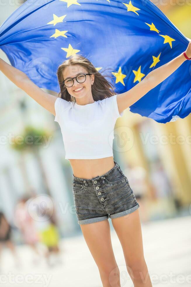 carino contento giovane ragazza con il bandiera di il europeo unione nel il strade da qualche parte nel Europa foto