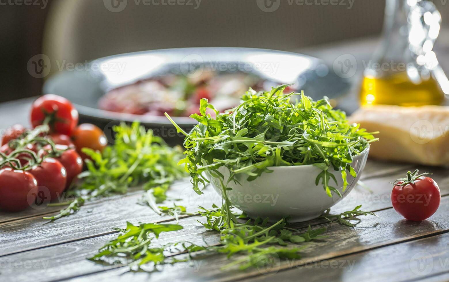 fresco rucola insalata nel bianca piatto su di legno tavolo foto