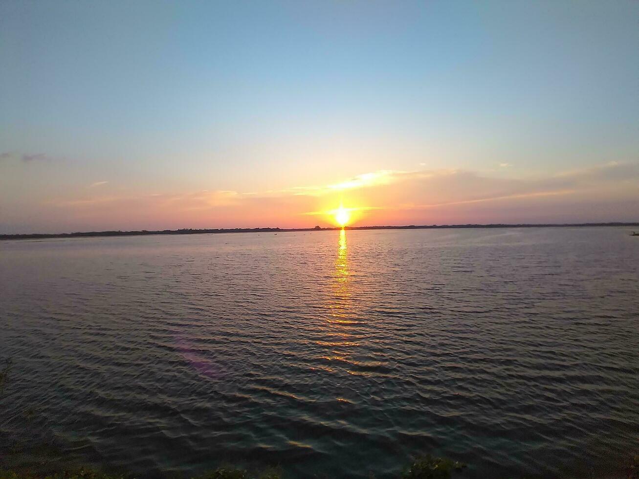 crepuscolo raggi e nuvole riflessa nel il calma acqua. tramonto Visualizza foto