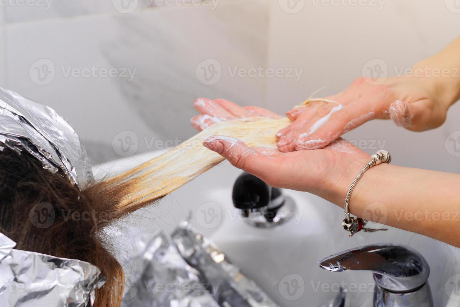 lavare la tintura per capelli da un parrucchiere, rimuovere la pellicola dai capelli. foto