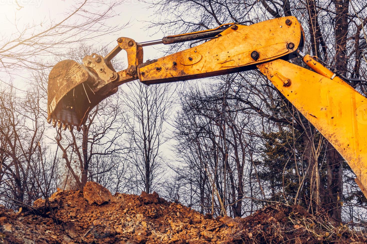 un vecchio escavatore giallo nel mezzo della foresta scava una fossa di mestolo per raccogliere l'acqua. foto
