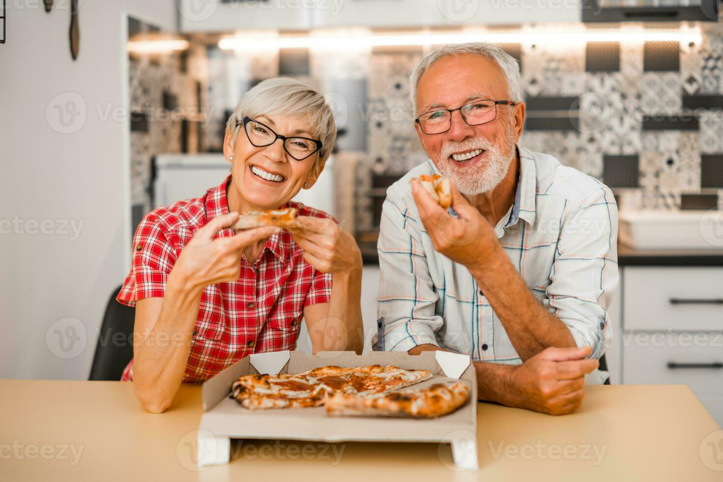 anziano coppia mangiare Pizza a casa. foto