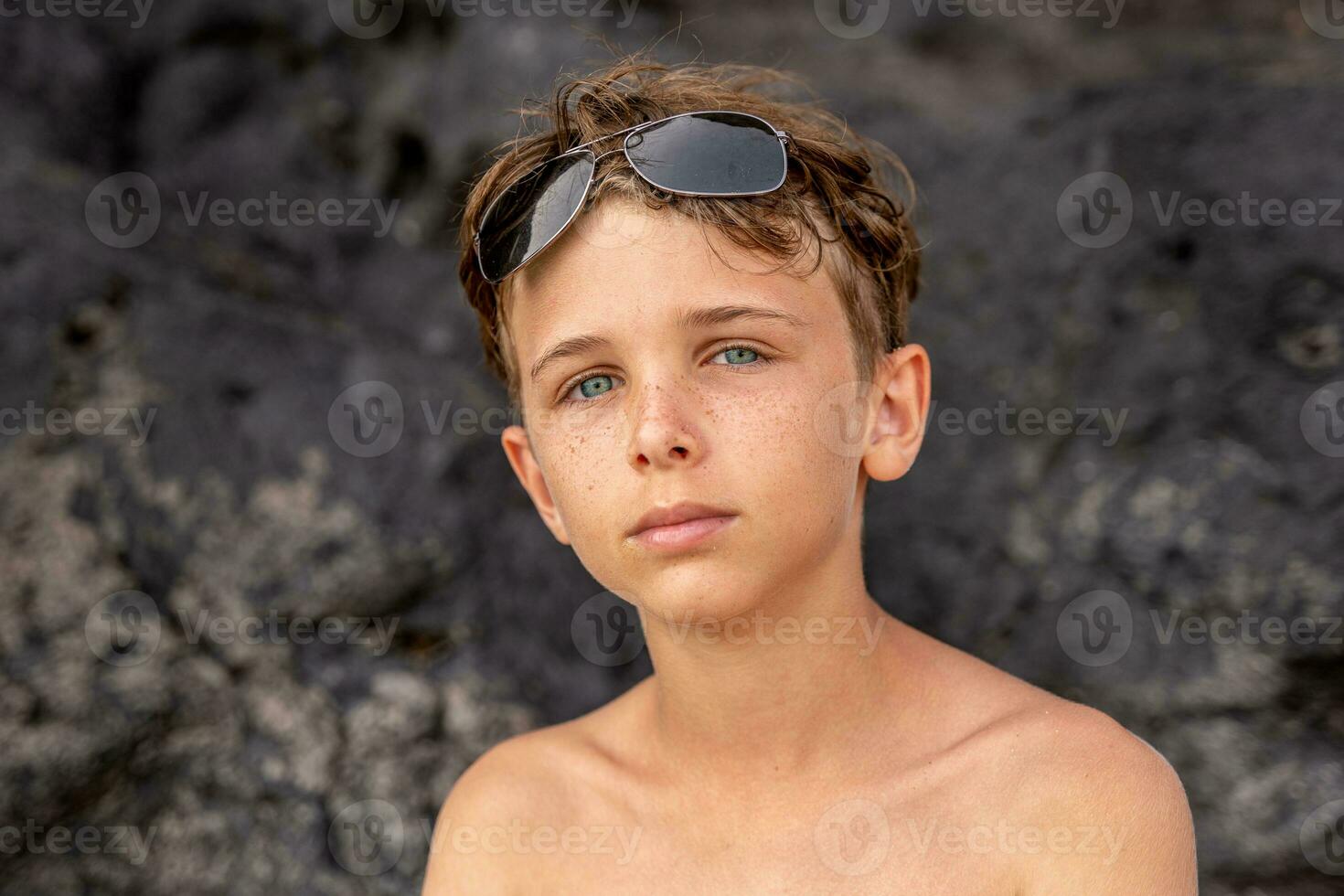 divertente ritratto di giovane A petto nudo uomo indossare occhiali da sole nel un esotico spiaggia foto