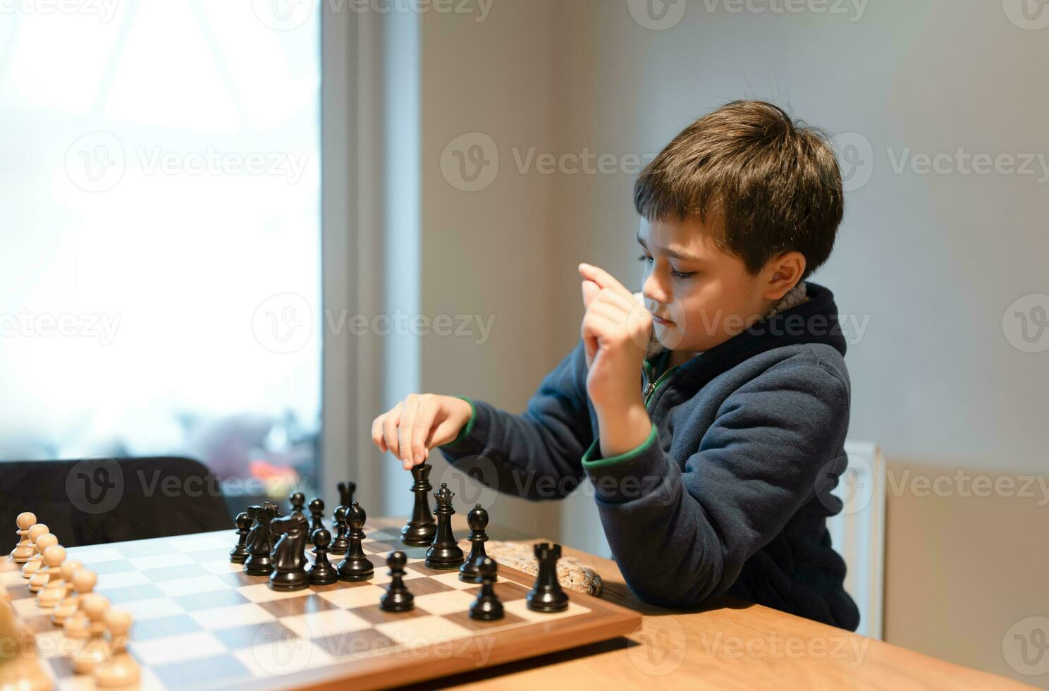 concentrato giovane ragazzo sviluppando scacchi strategia, giocando scacchiera gioco con amico o famiglia a casa. attività o passatempo per famiglia concetto foto