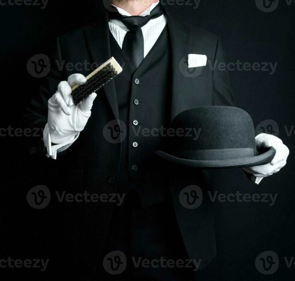 ritratto di maggiordomo nel buio formale completo da uomo e bianca guanti spazzolatura un' giocatore di bowling cappello. concetto di servizio industria e professionale ospitalità. foto