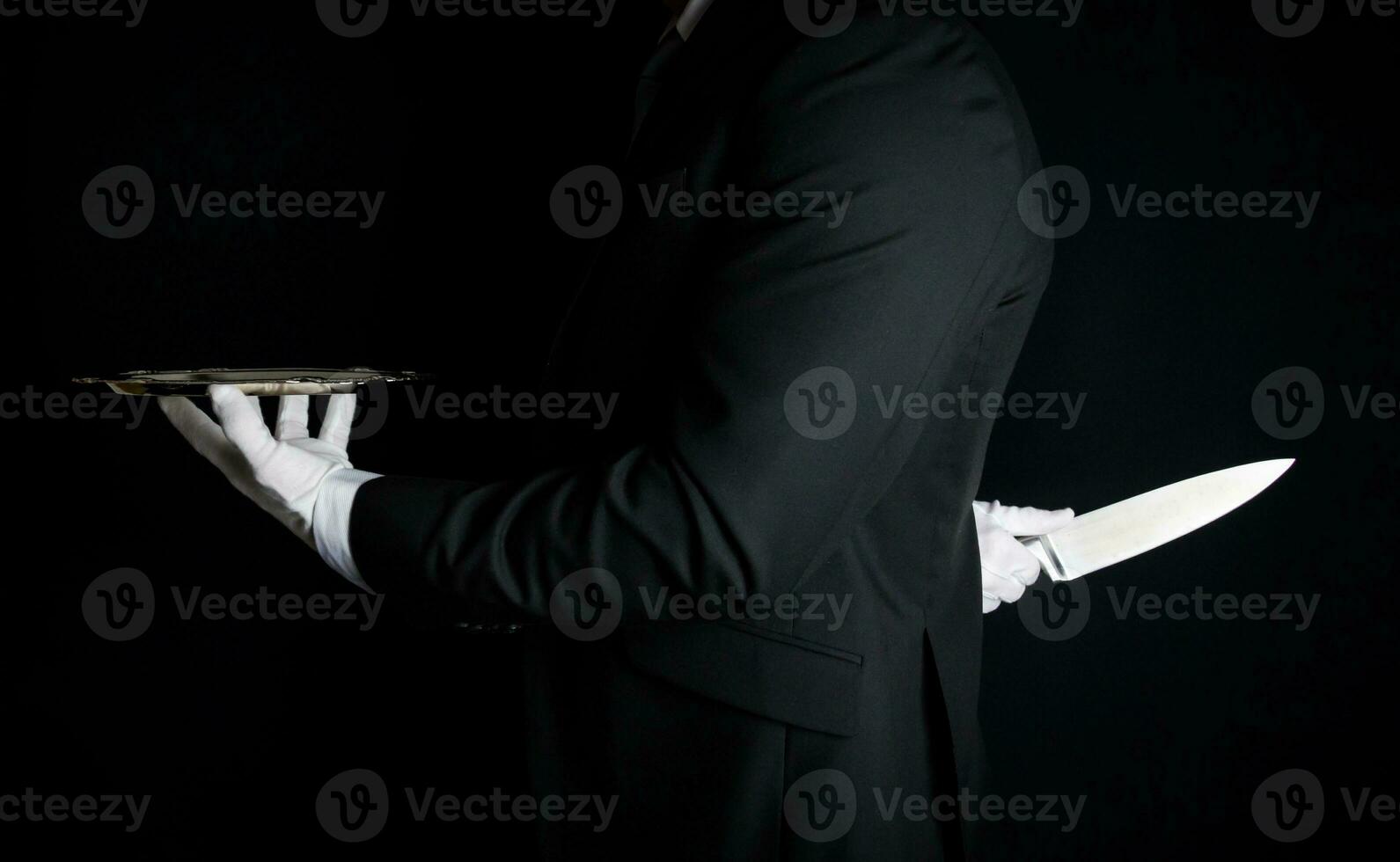 maggiordomo nel buio completo da uomo e bianca guanti con servendo vassoio e Tenere coltello dietro a il suo Indietro. concetto di maggiordomo fatto esso. foto