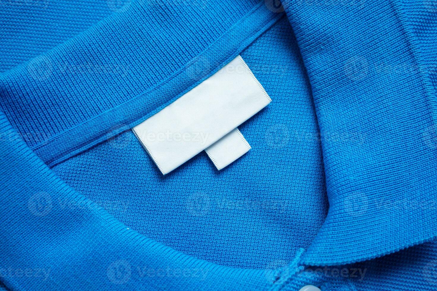 vuoto bianca lavanderia cura Abiti etichetta su blu camicia tessuto struttura sfondo foto