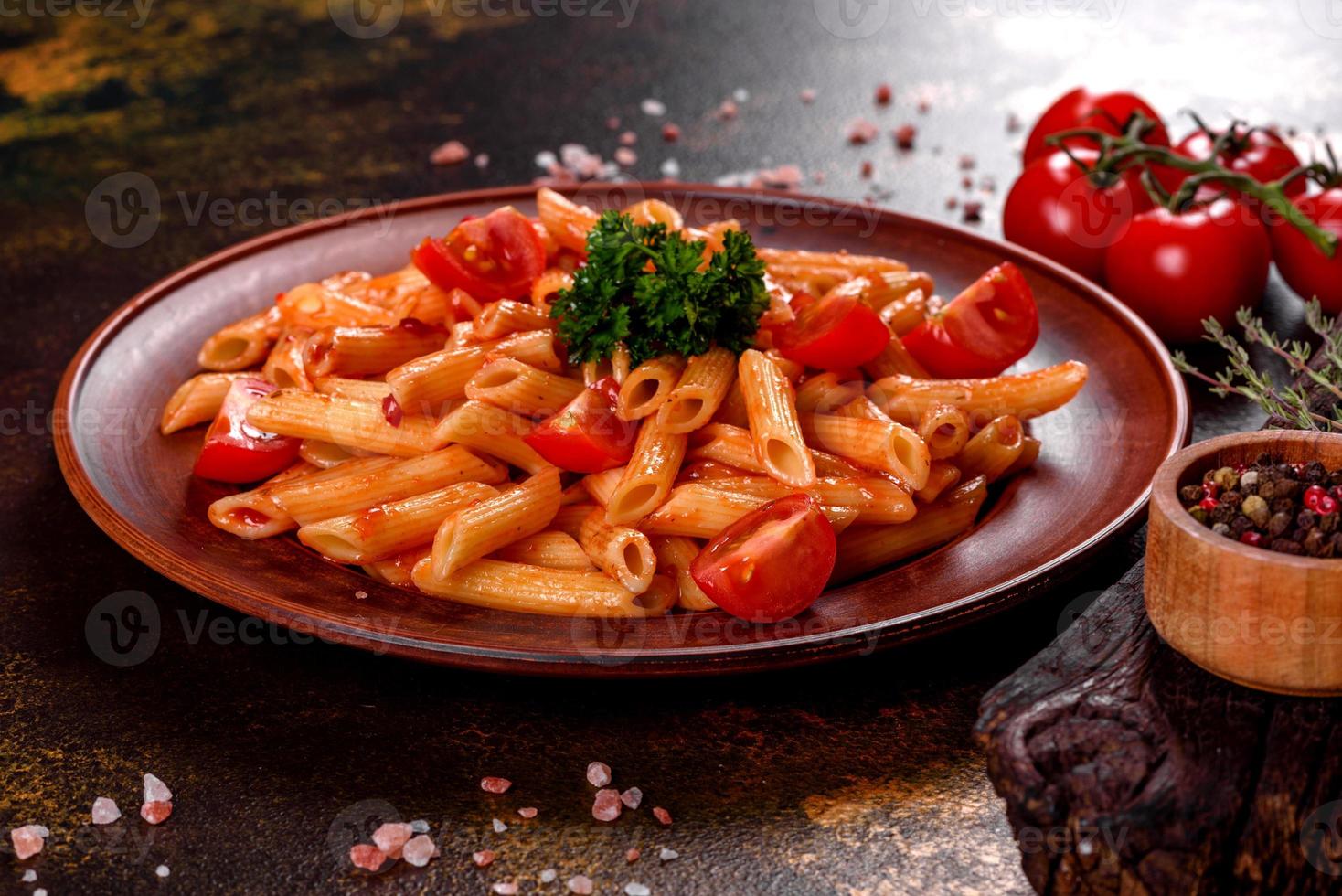 deliziosa pasta fresca con salsa di pomodoro con spezie ed erbe aromatiche su sfondo scuro foto