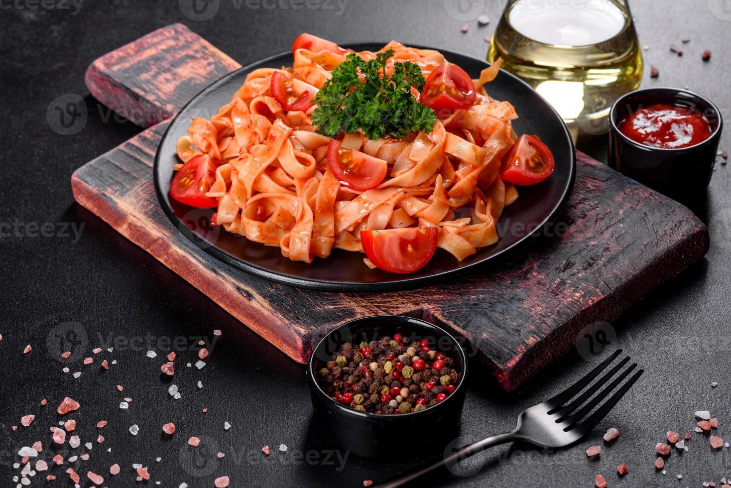 deliziosa pasta fresca con salsa di pomodoro con spezie ed erbe aromatiche su sfondo scuro foto