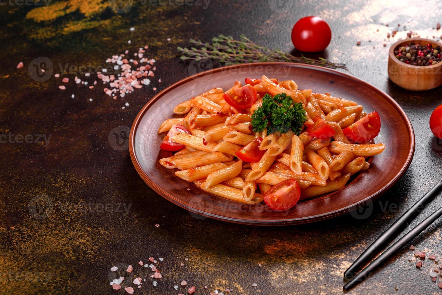 deliziosa pasta fresca con salsa di pomodoro con spezie ed erbe aromatiche su sfondo scuro foto