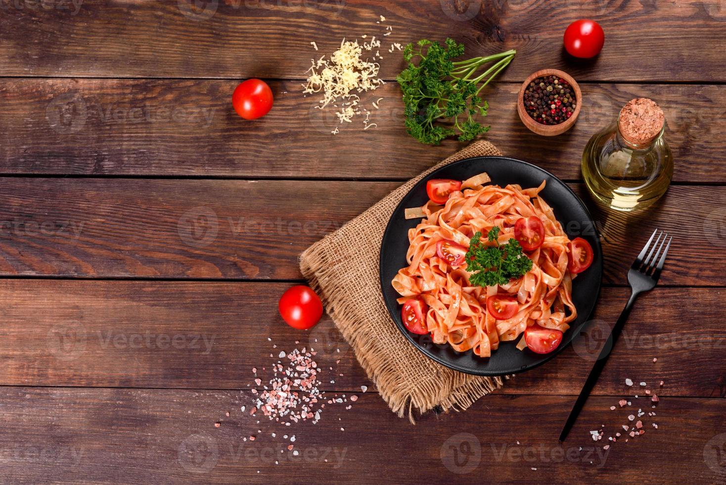 deliziosa pasta fresca con salsa di pomodoro con spezie ed erbe aromatiche su sfondo scuro foto