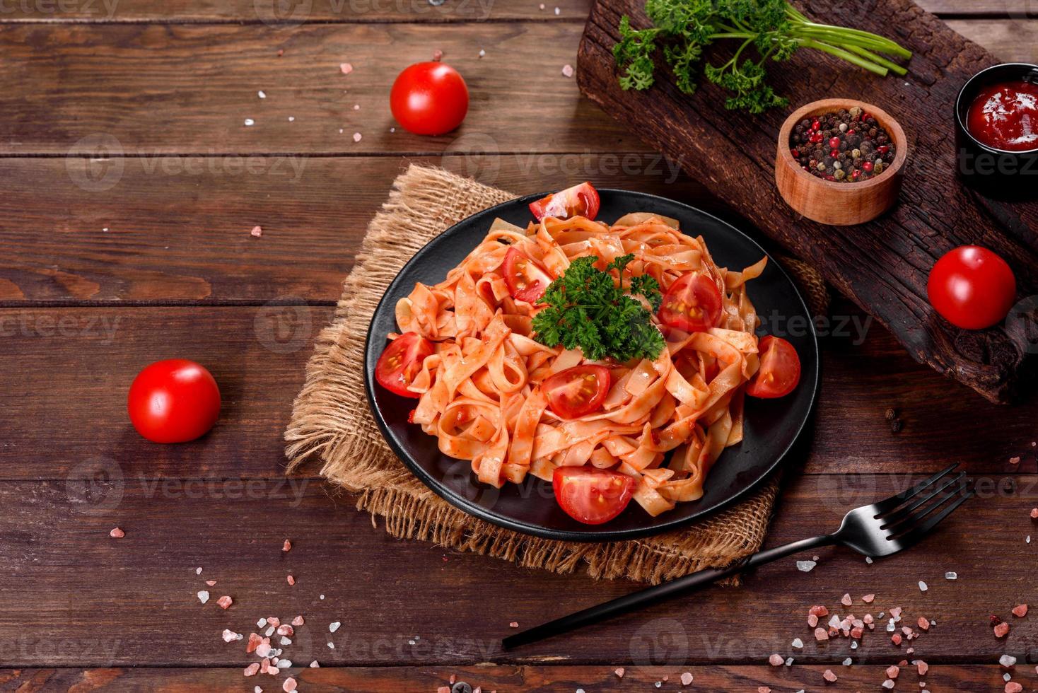 deliziosa pasta fresca con salsa di pomodoro con spezie ed erbe aromatiche su sfondo scuro foto