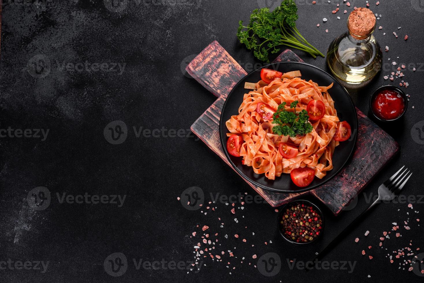 deliziosa pasta fresca con salsa di pomodoro con spezie ed erbe aromatiche su sfondo scuro foto