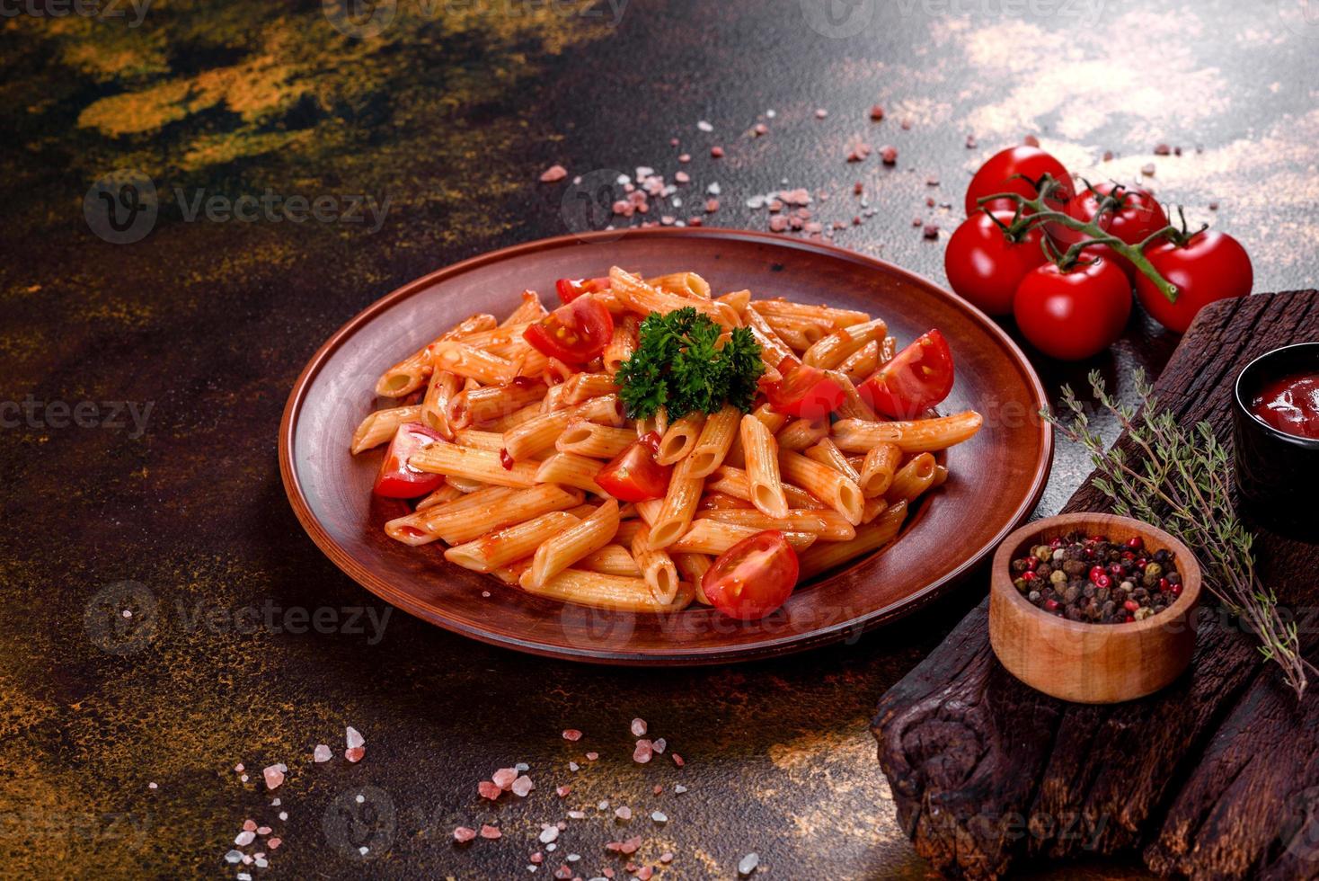 deliziosa pasta fresca con salsa di pomodoro con spezie ed erbe aromatiche su sfondo scuro foto