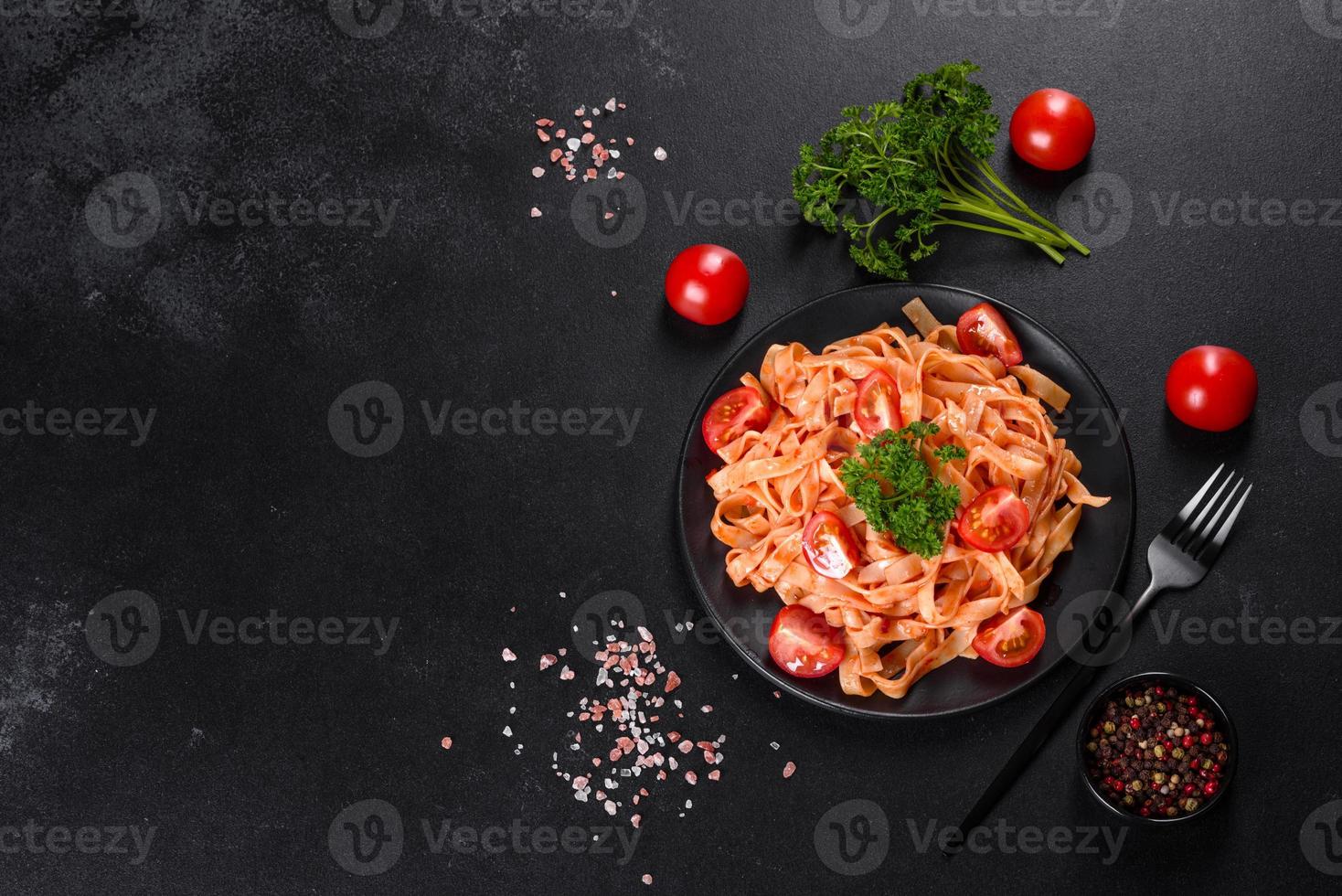 deliziosa pasta fresca con salsa di pomodoro con spezie ed erbe aromatiche su sfondo scuro foto