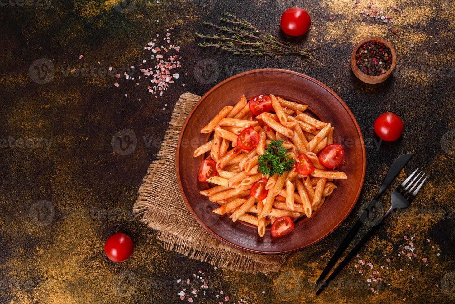 deliziosa pasta fresca con salsa di pomodoro con spezie ed erbe aromatiche su sfondo scuro foto