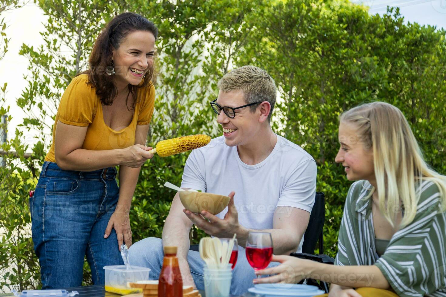 famiglia con madre e sua bambini Compreso fratello e sorella avendo bbq picnic vacanza a loro Giardino dietro la casa durante estate mentre avendo bene cibo e tempo insieme per amore e fratello concetto foto